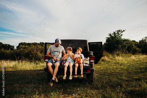 Dad and two kids having a picnic on truck tailgate