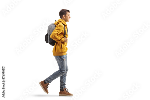 Full length profile shot of a male teenage student in a yellow hoodie walking photo