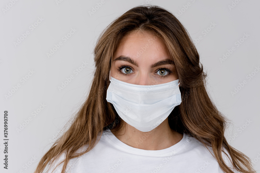 Studio portrait of young woman wearing a face mask, looking at camera, close up, isolated on gray background. Flu epidemic, dust allergy, protection against virus Studio portrait of young woman wearing a face mask, looking at camera, close up, isolated on gray background. Flu epidemic, dust allergy, protection against virus