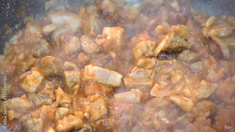 4K video recipe for making sauce, dressing or gravy with pieces of meat, onions and tomato paste and vegetables in a frying pan at high temperature close-up.Vegetable stew with meat 4K video recipe for making sauce, dressing or gravy with pieces of meat, onions and tomato paste and vegetables in a frying pan at high temperature close-up.Vegetable stew with meat