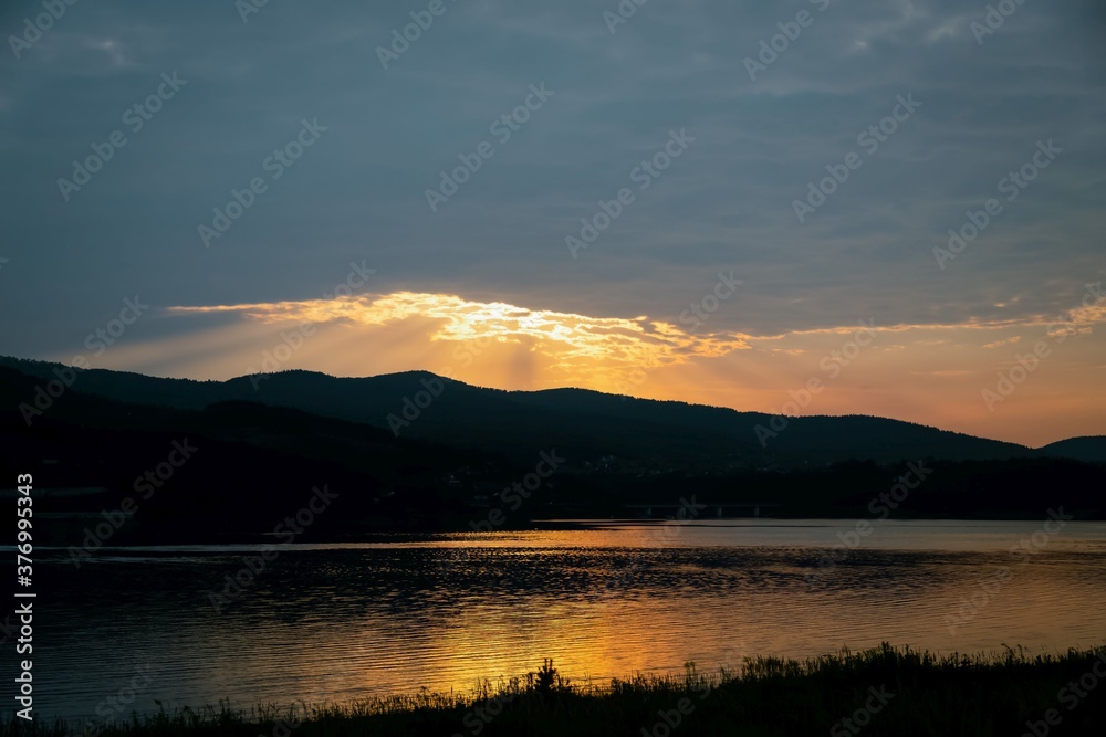 Beautiful golden sunset reflected in lake water. Lake Mucharz. Jezioro Mucharskie, Poland Beautiful golden sunset reflected in lake water. Lake Mucharz. Jezioro Mucharskie, Poland