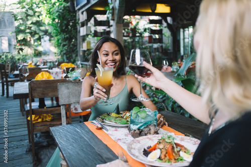 Females smiling and clinking drinks in exotic outdoor restaurant