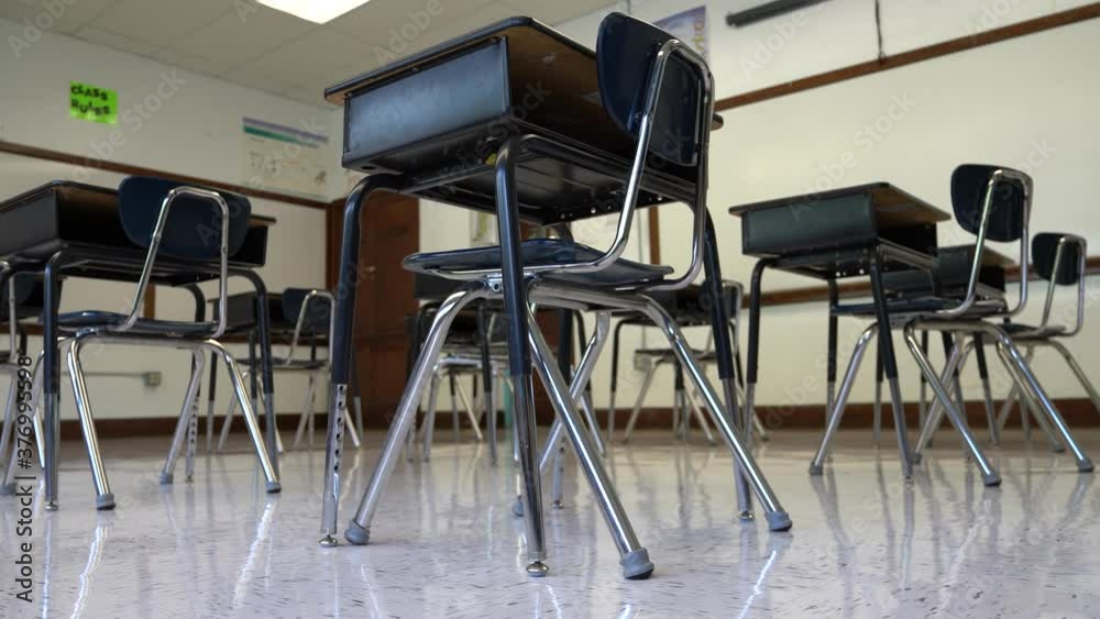 Floor view motion to the right showing empty school classroom with chairs under desks. Concept for pandemic.