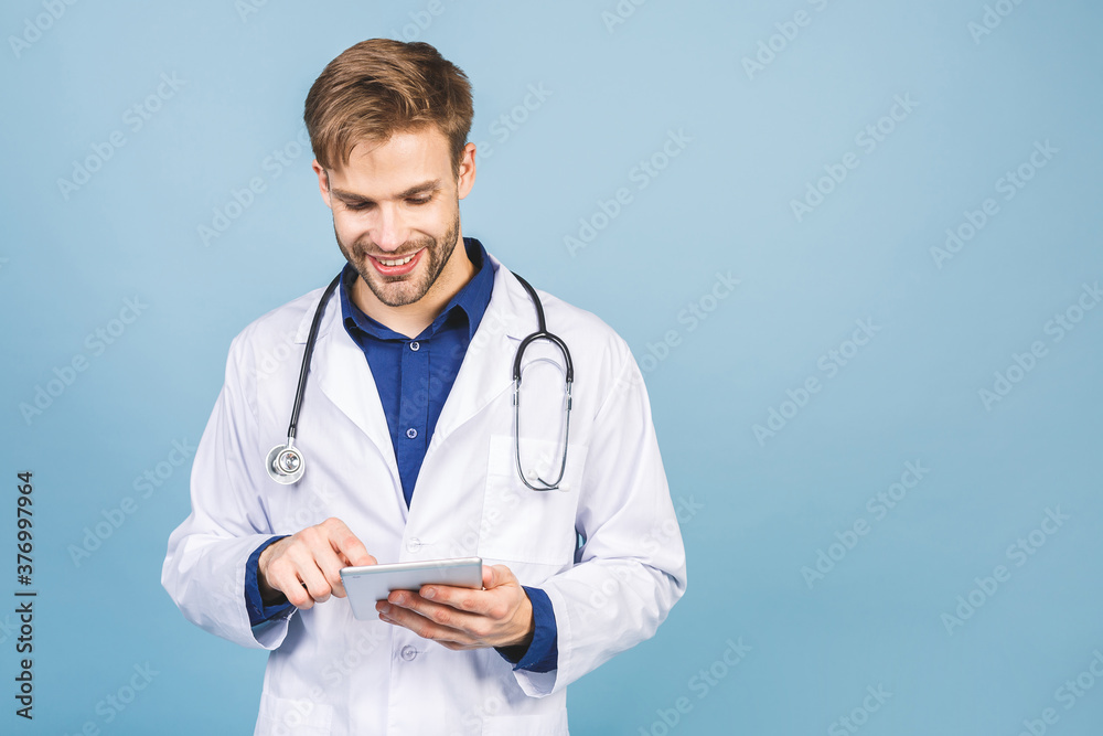 Smiling doctor using a tablet computer isolated on a blue background. Smiling doctor using a tablet computer isolated on a blue background.