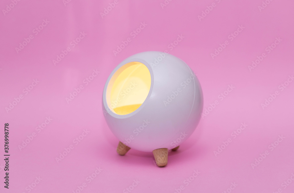 white night lamp in the shape of a ball on legs on a pink background.Children's lamp. with place for text white night lamp in the shape of a ball on legs on a pink background.Children's lamp. with place for text