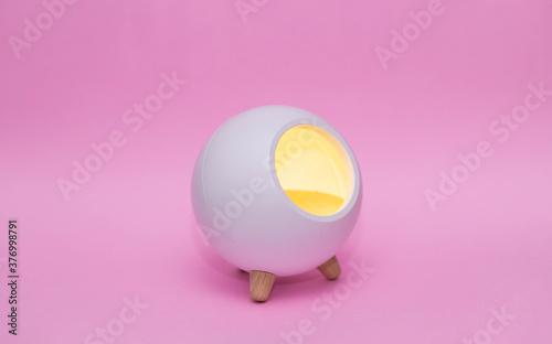 white night lamp in the shape of a ball on legs on a pink background.Children's lamp. with place for text
