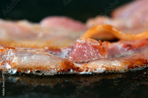 Macro view of bacon slice in frying pan.