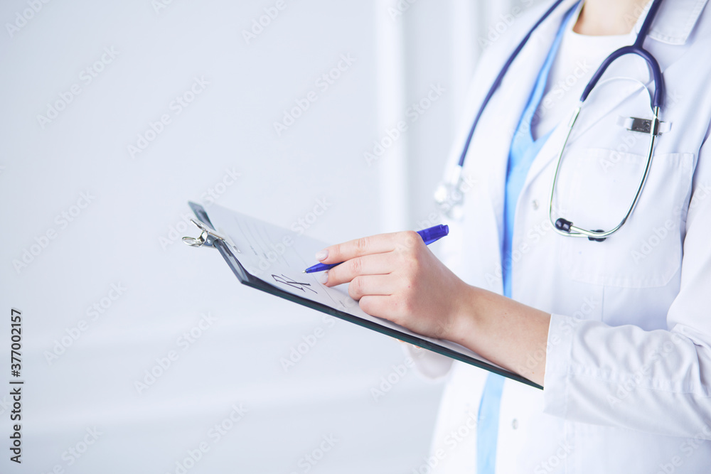 Young smiling female doctor with stethoscope holding a folder at a hospital's consulting room Young smiling female doctor with stethoscope holding a folder at a hospital's consulting room