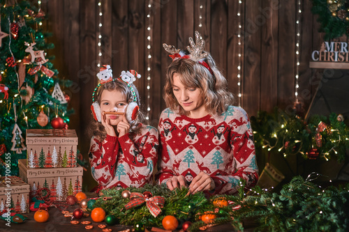 mother with child girl near christmas tree. new year holidays. happy family. woman with daughter having fun and smiling, making faces.