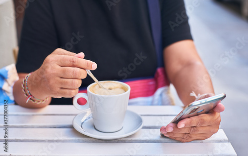 Woman s hands using a mobile phone and having a coffee on a terrace