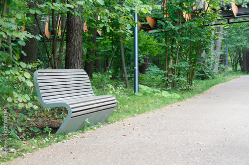 Fototapeta Naklejka Na Ścianę i Meble -  Bench in a green park by the trail.