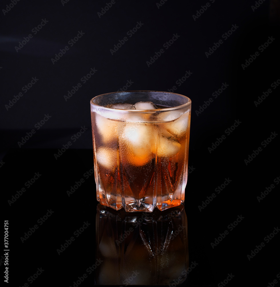 misted glass of whiskey with ice on black background misted glass of whiskey with ice on black background