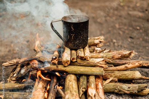 metal mug on the background of fire, picnic with fire in the forest