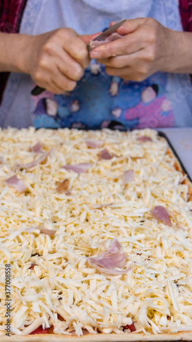 elderly woman white mother cutting sausages and sausages to make pizza