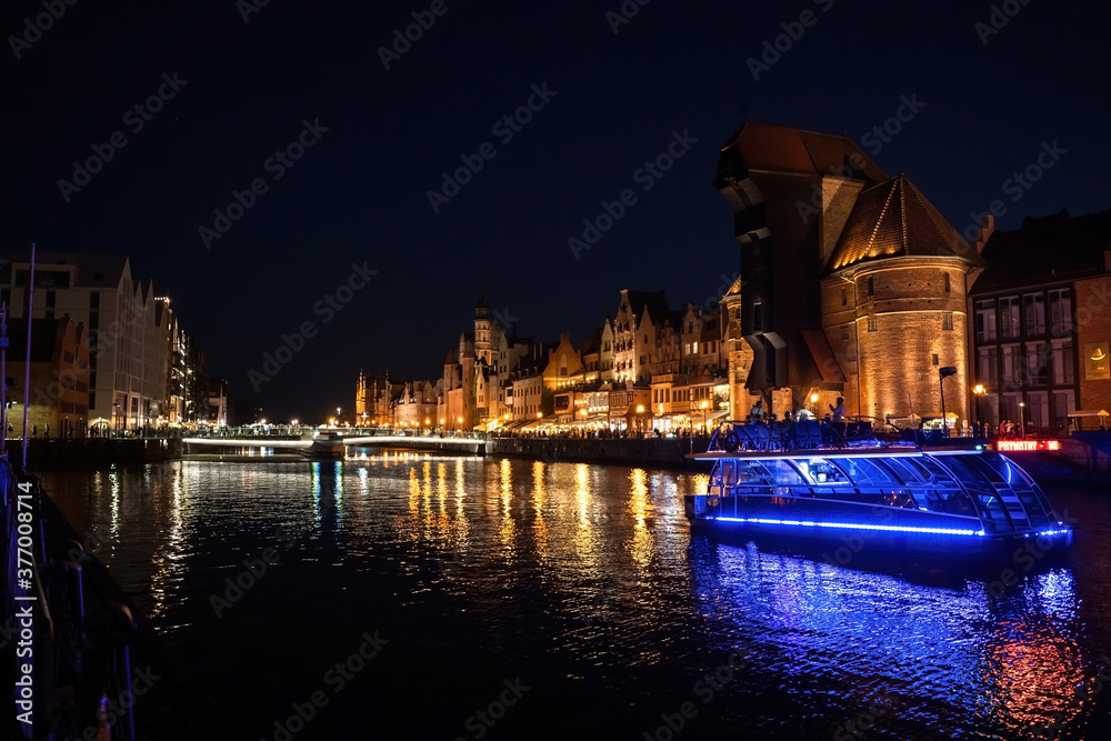 Fototapeta premium Gdansk, North Poland - August 15, 2020: Wide angle panoramic Night photography of polish cityscape with polish architecture in the old town over motlawa river near baltic sea