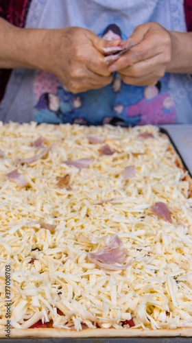 elderly woman white mother cutting sausages and sausages to make pizza