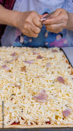 elderly woman white mother cutting sausages and sausages to make pizza