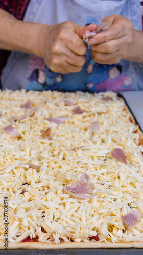 elderly woman white mother cutting sausages and sausages to make pizza