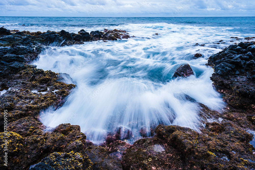 Fototapeta premium Waves crashing over lava rocks, Kauai