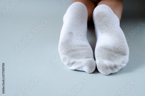 Pair of child feet in dirty stained white socks. dirty socks 