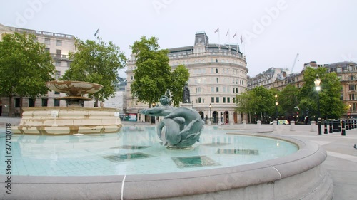 Lockdown in London, Slow motion Gilmbal pan of Empty Trafalgar Square fountain during coronavirus pandemic 2020, with one lone police car & flying birds.