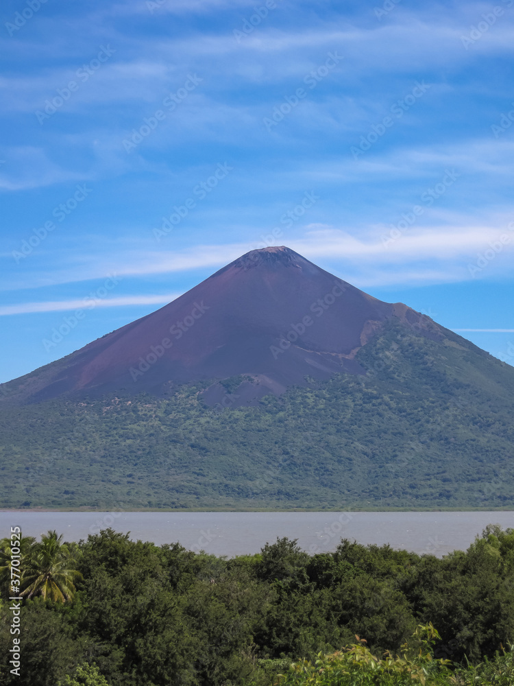 Leon, Nicaragua - November 27, 2008: Ruins of old Leon. Portrait of Momotombo volcano mountain seen from the ruins under blue sky with white stripes. Brown water of lake Xolotian. Leon, Nicaragua - November 27, 2008: Ruins of old Leon. Portrait of Momotombo volcano mountain seen from the ruins under blue sky with white stripes. Brown water of lake Xolotian.