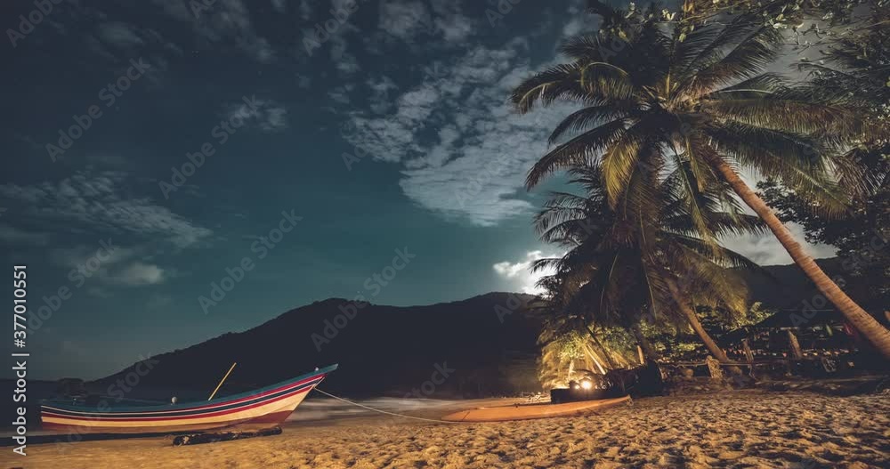 Boat at sand ocean beach timelapse at night scenery of Koh Phangan Island, Thailand, Asia. Magnificent landcape with tropical palms and mountains silhouette. Nobody cinematic shot
