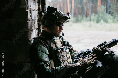 Weapon inspection while waiting on a spot. Military man checks his assault rifle preparing for operation.