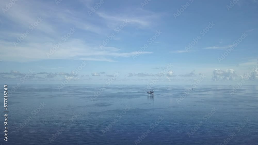 Aerial view from a drone of an offshore jack up rig and offshore supply vessels at the offshore location during day time
