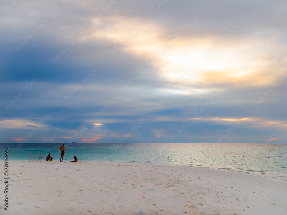 People on a sandy island at sunset in the Indian ocean near the Maldives