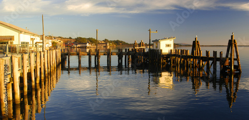 Dock in Bodega Bay, California, reflecting in calm water near sunset photo