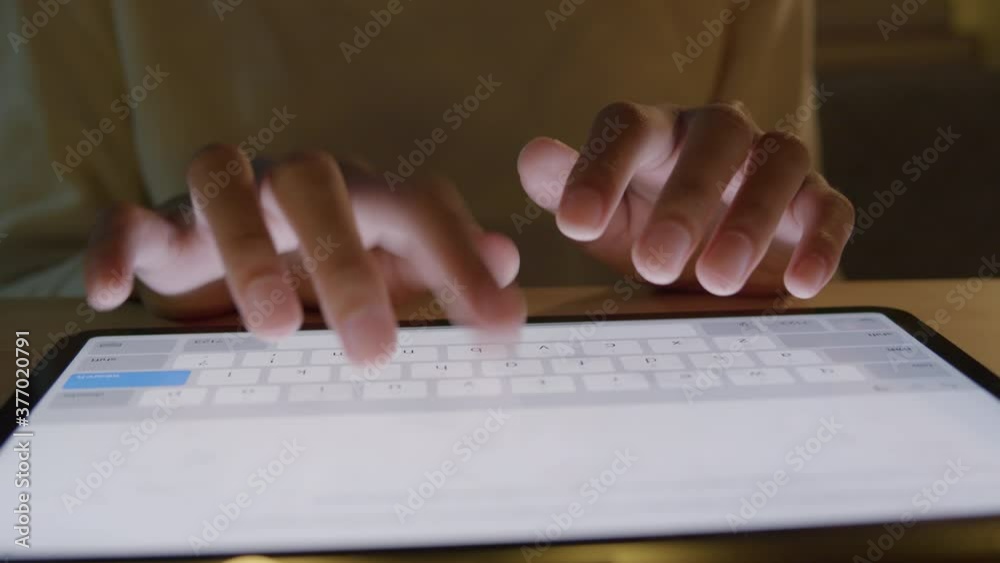 Close up. Hand of Asian girl typing on a keyboard on the table at night Close up. Hand of Asian girl typing on a keyboard on the table at night