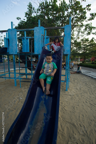 Two small children playing a slide in the city park of Bojonegoro, Indonesia photo