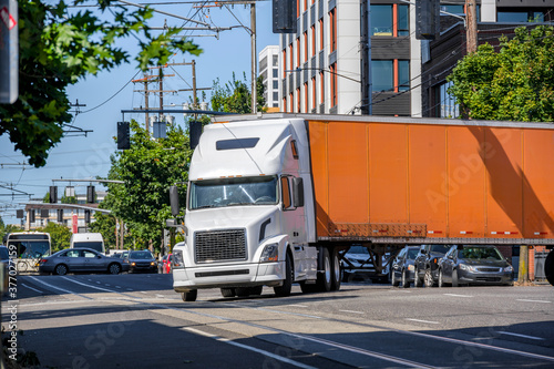 Canvas Print Big rig semi truck with long dry van semi trailer turning on the crossroad stree