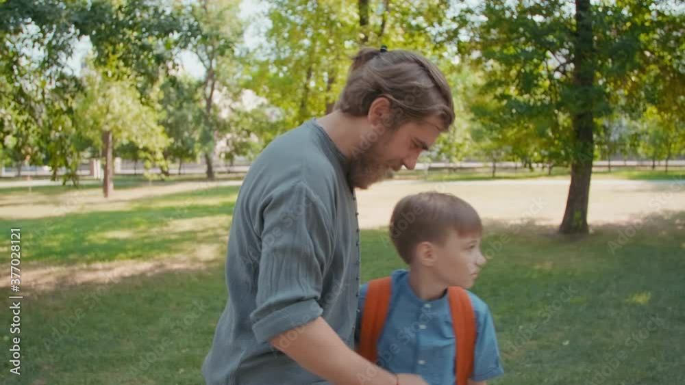 Slowmo shot of bearded father hugging cute schoolboy after taking him to school on sunny morning Slowmo shot of bearded father hugging cute schoolboy after taking him to school on sunny morning
