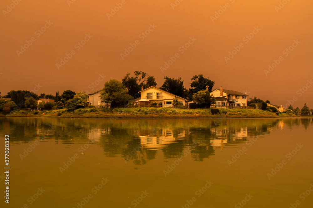 Fototapeta premium Orange Skies Over Suburban Lake Due to August Complex Fires in California
