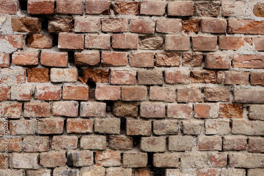 Old cracked and damaged red brick wall. Background of an old brick house texture. Old cracked and damaged red brick wall. Background of an old brick house texture.