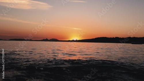Relaxing scene of the water in the sea with a sunset in the horizon over the coastline