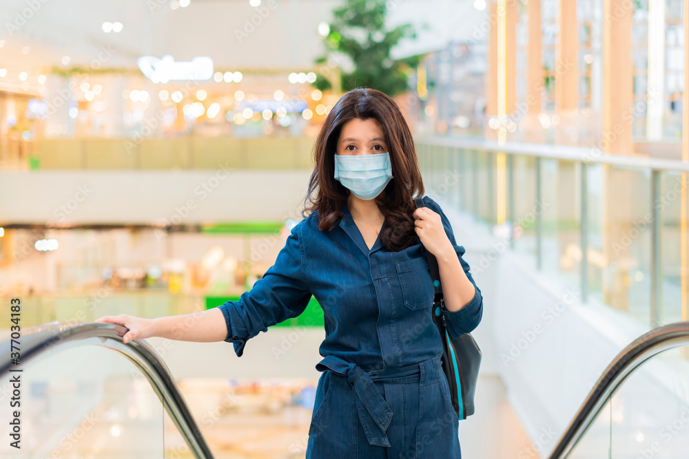 Obraz premium Virus mask Asian woman travel wearing face protection in prevention for coronavirus. Lady walking in public space bus station or airport.