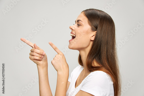 Cheerful woman with open mouth shows her fingers towards 
