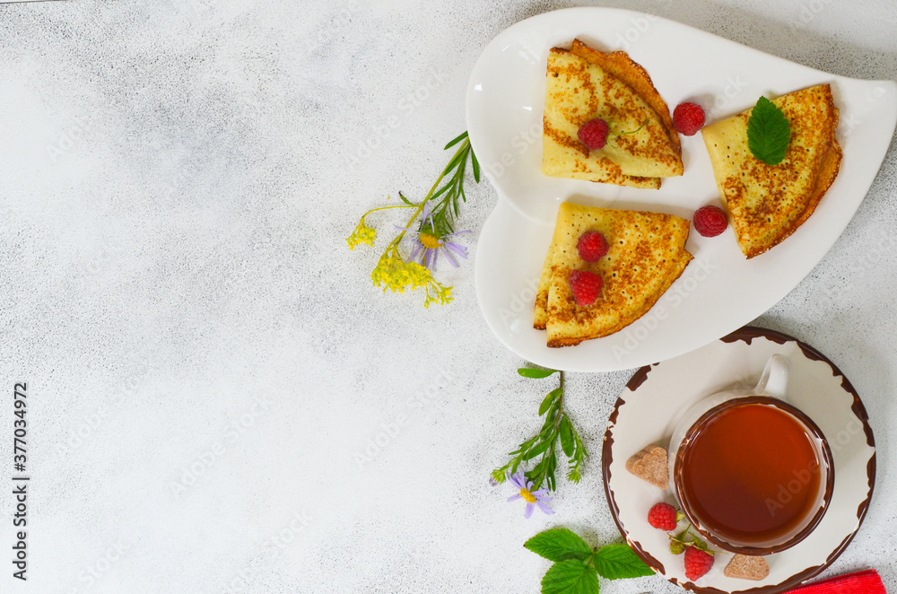 Delicious homemade pancakes with raspberries and a cup of tea top view flat lay with copy space for text and design. Concept of celebrating the Maslenitsa holiday.