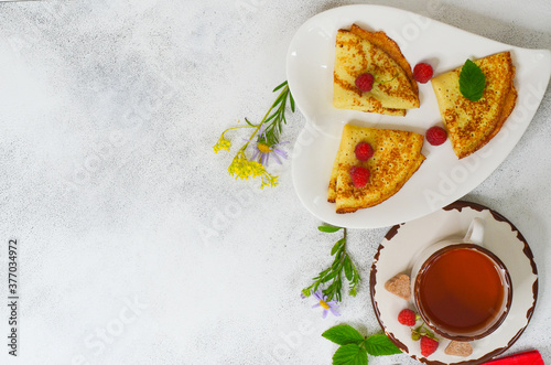 Delicious homemade pancakes with raspberries and a cup of tea top view flat lay with copy space for text and design. Concept of celebrating the Maslenitsa holiday.