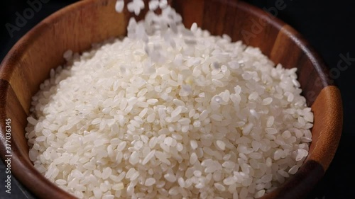 Japanese rice falling in slow motion. Raw rice grain in wooden bowl
