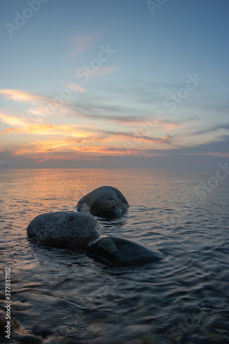 Three large stones above the water surface at sunset