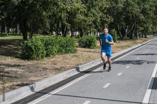 Handsome man jogging in the park. Sportsman runs exercising training outdoors.