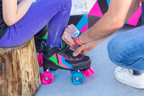 Father placing roller skates on his daughter