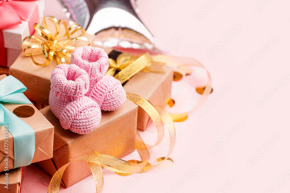 Beautiful composition with pink baby booties and gift box on pink background. Concept of baby shower party, first birthday holiday card, copy space