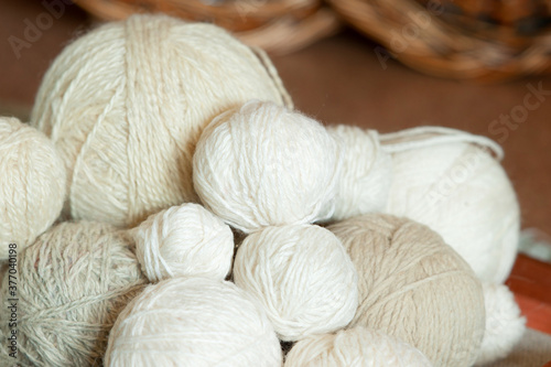 many balls of light wool threads of different sizes and shades, knitting materials