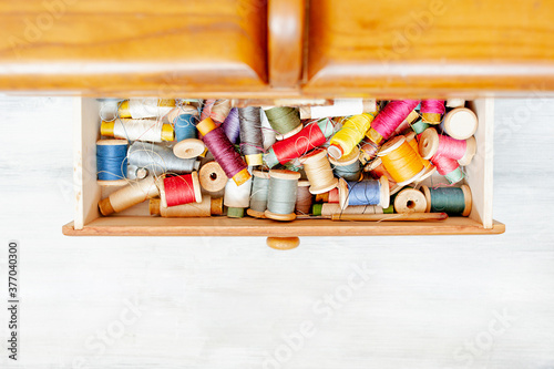 lots of colorful balls of thread in wooden box, tools for sewing hobby, top view