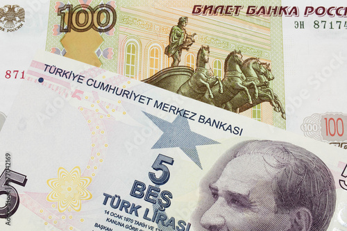 A macro image of a Russian one hundred ruble note paired up with a purple, five real bank note from Turkey. Shot close up in macro.
